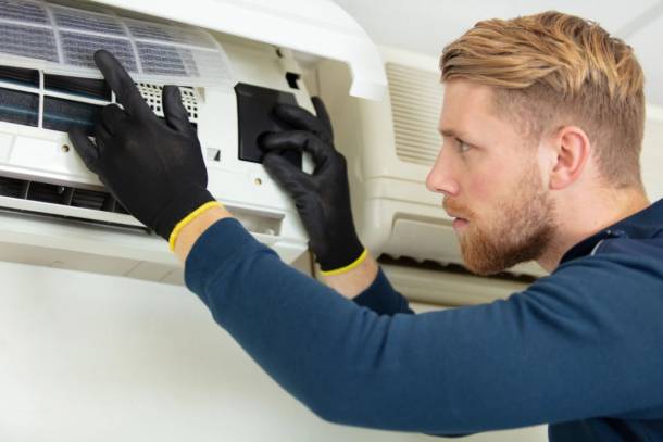 Technician repairing wall-mounted air-conditioning unit