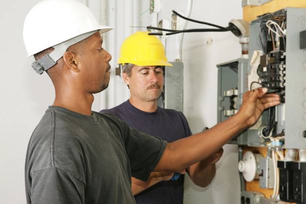 two electricians working on a panel