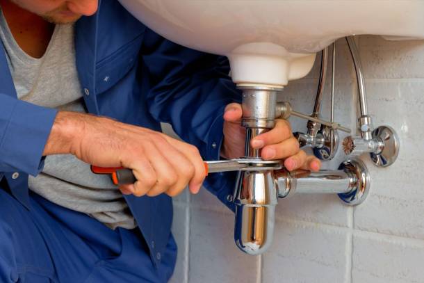 plumber using tools to fix pipe under the sink