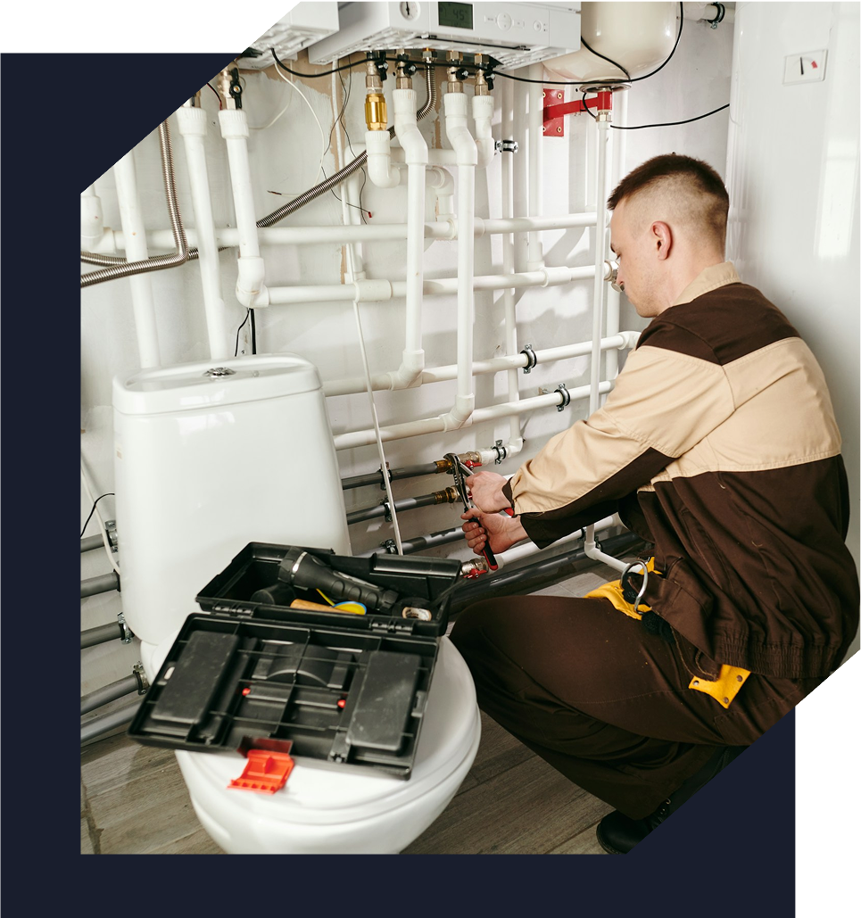 Plumber using pliers on plumbing behind toilet