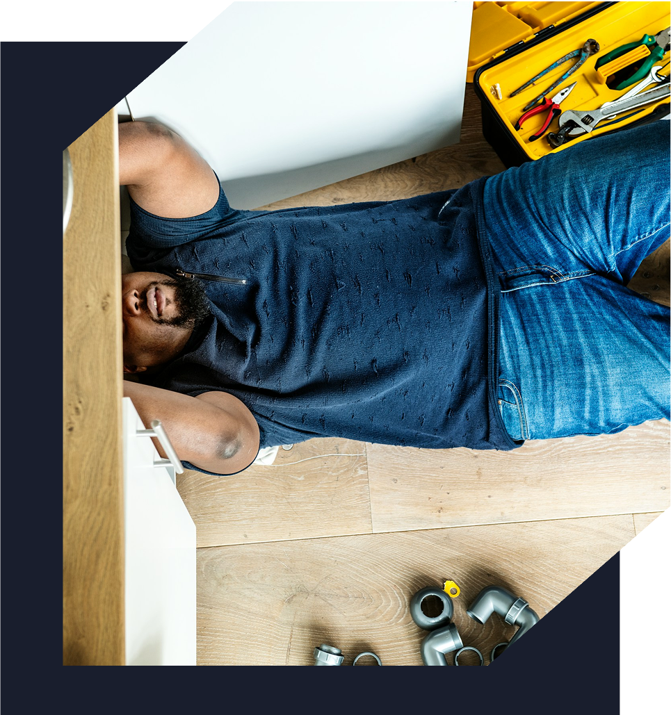 Plumber under cabinets fixing pipes